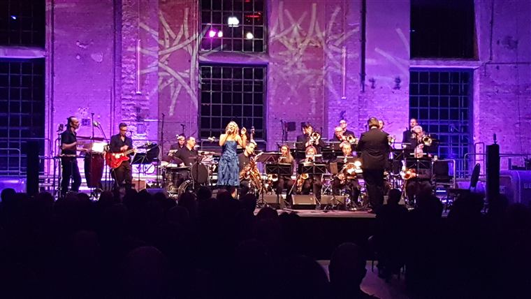 Bigband mit Sängerinnen auf violett beleuchteter Bühne